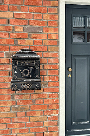 Wall-mounted letterbox with newspaper roll (Art.-Nr. 1524 AZ) and personalised letter slot.
Letterbox painted black with antique bronze patina.